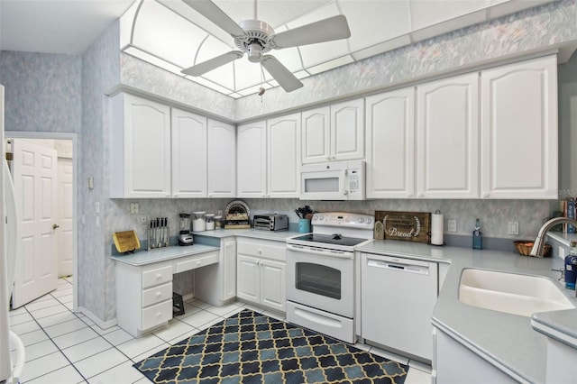 kitchen featuring white appliances, wallpapered walls, ceiling fan, white cabinetry, and a sink