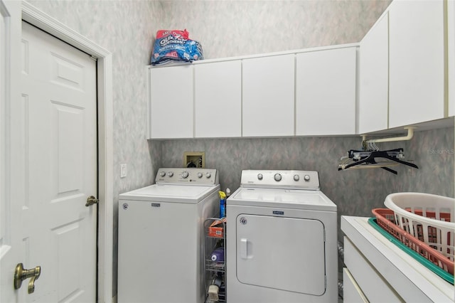 laundry room featuring cabinet space, washer and clothes dryer, and wallpapered walls