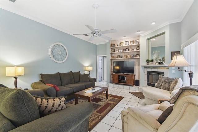 living room featuring light tile patterned floors, ceiling fan, built in shelves, a tile fireplace, and ornamental molding