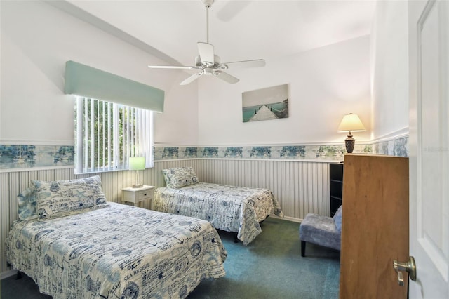 carpeted bedroom with lofted ceiling, wainscoting, and a ceiling fan