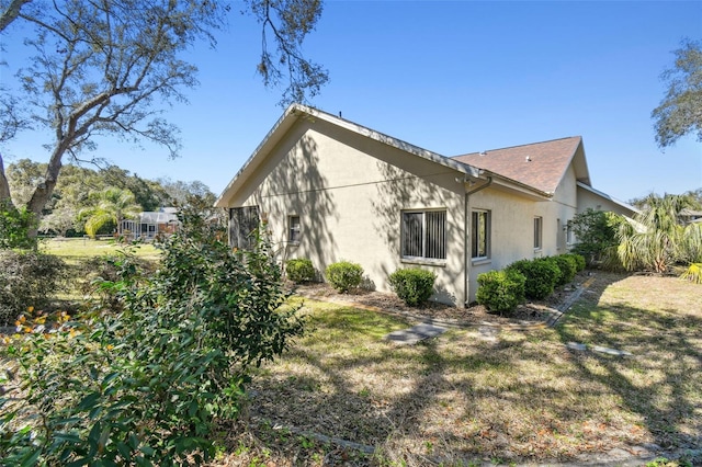 view of side of home featuring a lawn and stucco siding