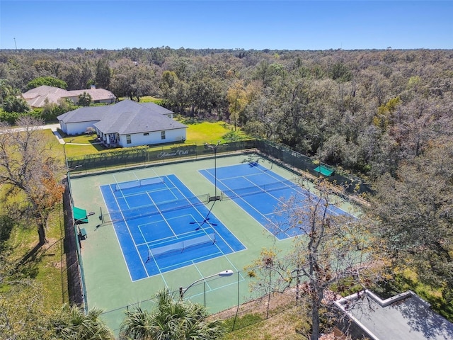 view of tennis court with fence and a view of trees