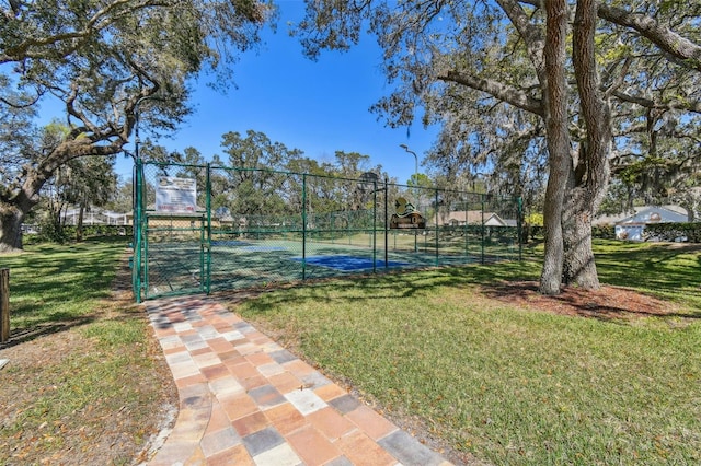 view of sport court featuring a gate, fence, and a yard