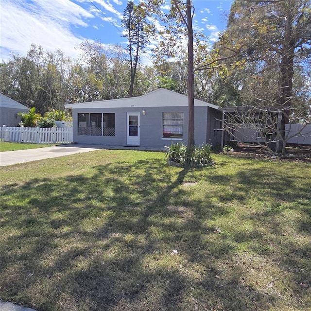 view of front of house with fence, concrete block siding, and a front yard