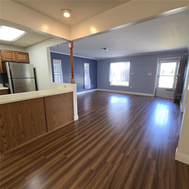 unfurnished living room with a healthy amount of sunlight, baseboards, and dark wood-style flooring