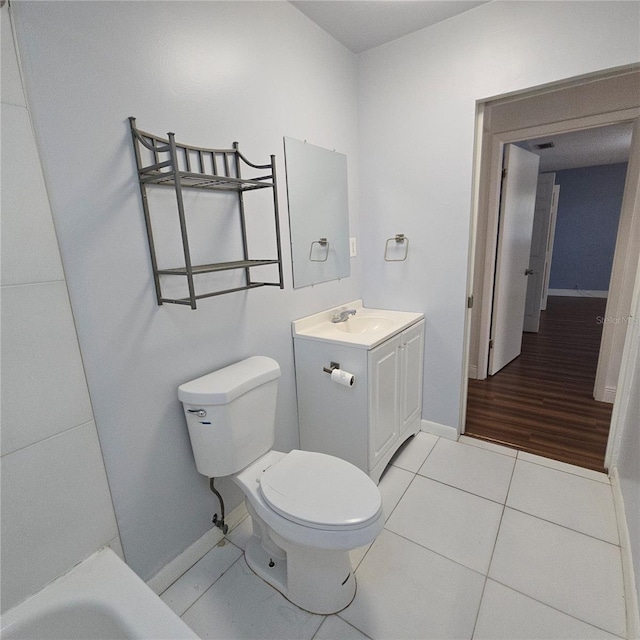 bathroom featuring baseboards, toilet, tile patterned flooring, vanity, and a bath