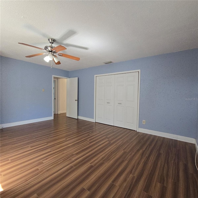 unfurnished bedroom featuring a closet, ceiling fan, a textured ceiling, wood finished floors, and baseboards