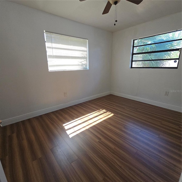 spare room featuring ceiling fan, dark wood-style flooring, and baseboards