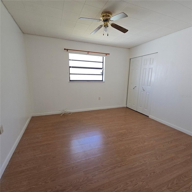 empty room with ceiling fan, baseboards, and wood finished floors