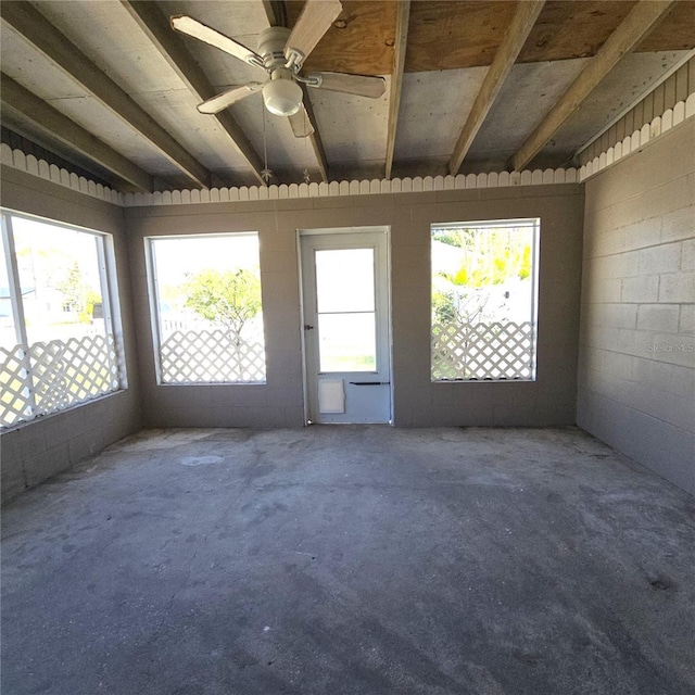 interior space with concrete flooring, ceiling fan, and concrete block wall