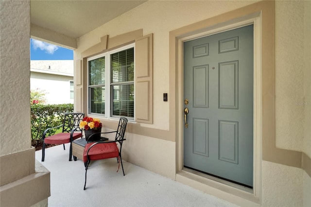 property entrance featuring a porch and stucco siding