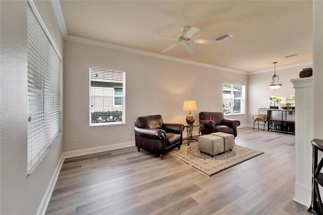 living area featuring baseboards, light wood-type flooring, visible vents, and crown molding