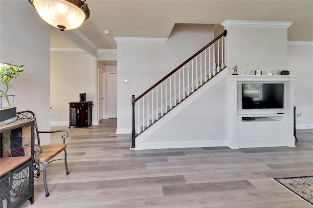 entrance foyer featuring stairs, ornamental molding, baseboards, and light wood-style floors