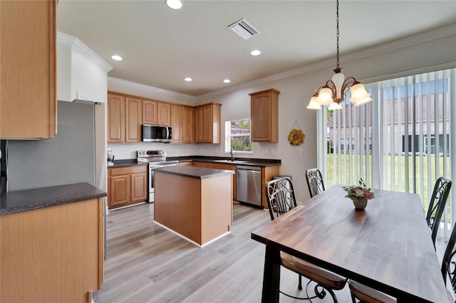 kitchen with visible vents, dark countertops, a kitchen island, stainless steel appliances, and a sink