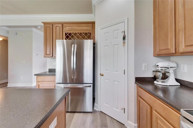 kitchen featuring ornamental molding, freestanding refrigerator, light wood-style flooring, and dark countertops