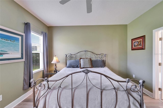 bedroom with a ceiling fan, baseboards, and wood finished floors