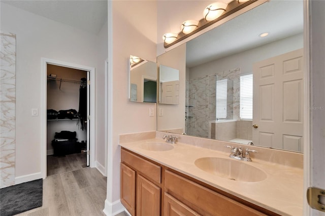 bathroom featuring a bath, a spacious closet, walk in shower, and a sink