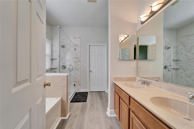 bathroom with a garden tub, wood finished floors, a sink, and a shower stall