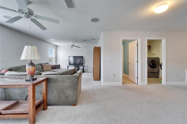 living room with visible vents, washer / clothes dryer, a textured ceiling, and light colored carpet