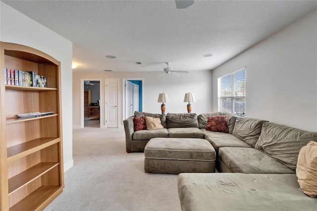 living area with a textured ceiling, visible vents, baseboards, a ceiling fan, and carpet