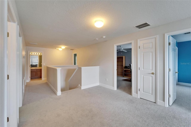 interior space featuring carpet, visible vents, a textured ceiling, and baseboards