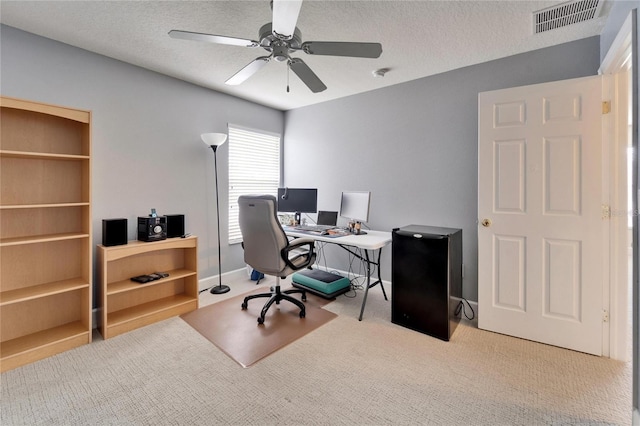 home office featuring carpet, visible vents, and a textured ceiling