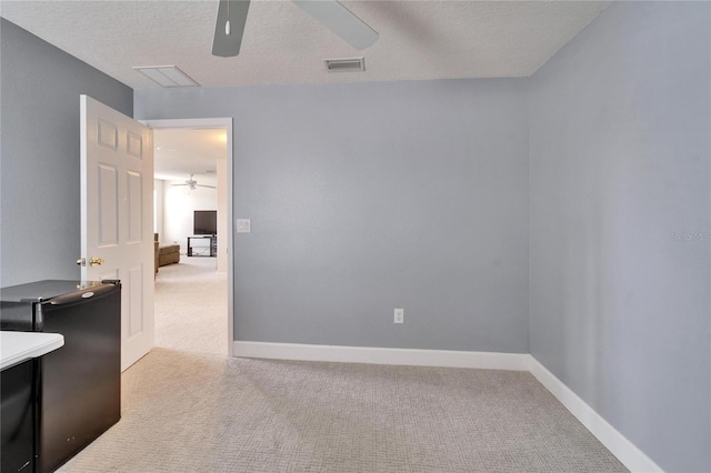 carpeted empty room with ceiling fan, a textured ceiling, visible vents, and baseboards