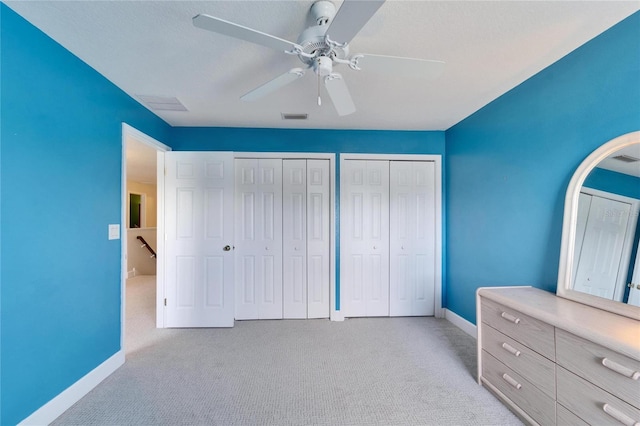 unfurnished bedroom featuring carpet floors, baseboards, visible vents, and multiple closets