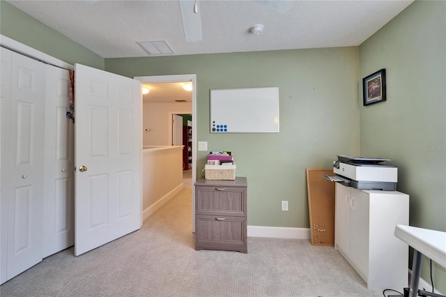 office space with light colored carpet, a textured ceiling, and baseboards