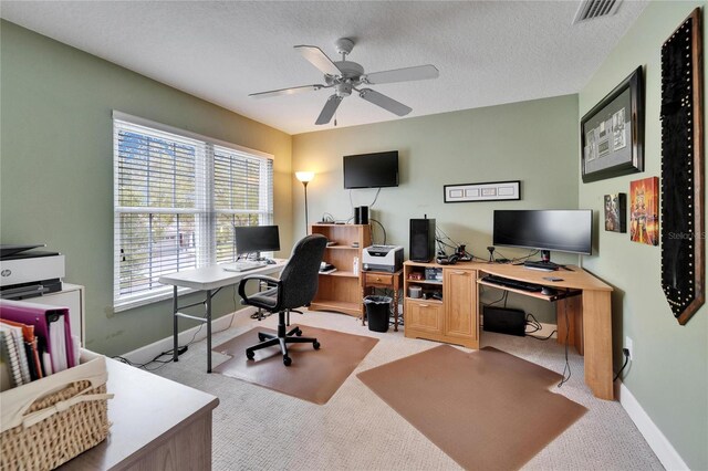 carpeted office space with baseboards, ceiling fan, visible vents, and a textured ceiling