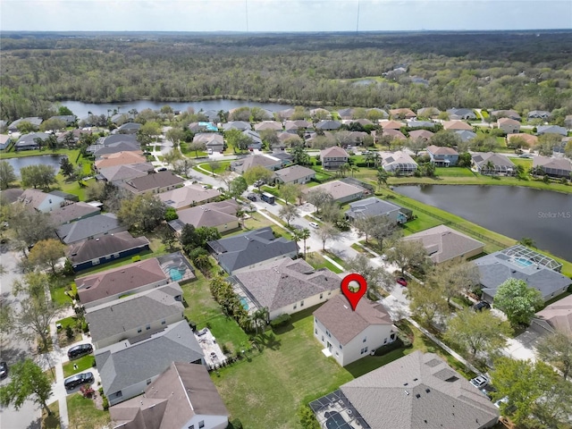 drone / aerial view featuring a residential view, a water view, and a view of trees