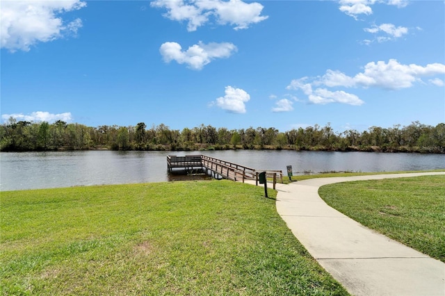 dock area featuring a water view, a lawn, and a wooded view