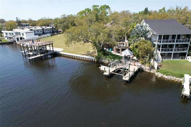 view of dock with a water view, boat lift, and a lawn