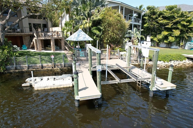 view of dock featuring stairway, a water view, boat lift, and a fenced backyard