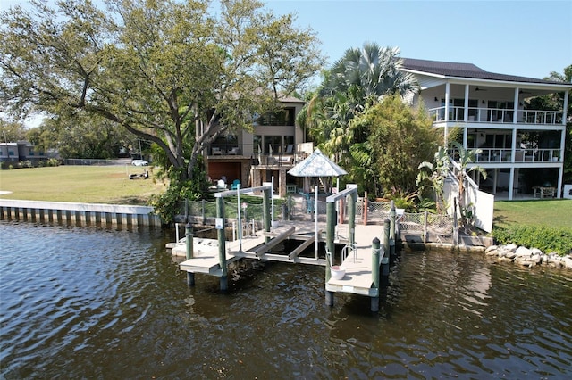 view of dock with a water view, a yard, and boat lift