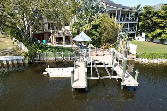 dock area featuring a water view, fence private yard, stairs, and a lawn