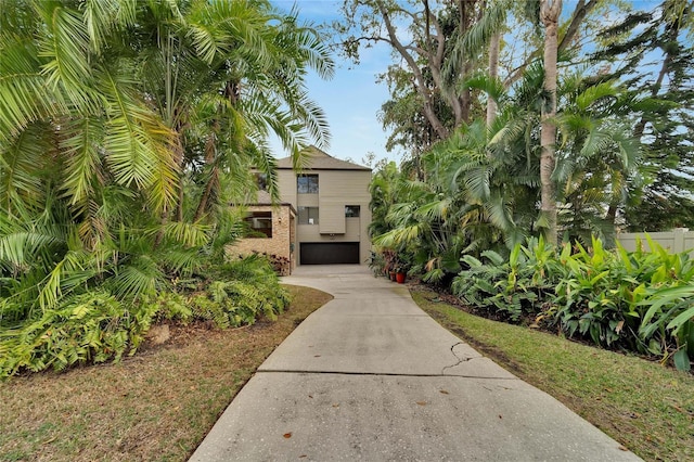 exterior space featuring fence, concrete driveway, and brick siding