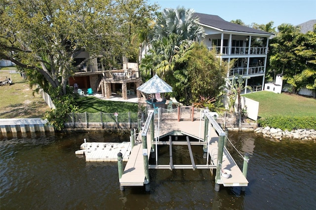 dock area featuring a water view, a lawn, and fence