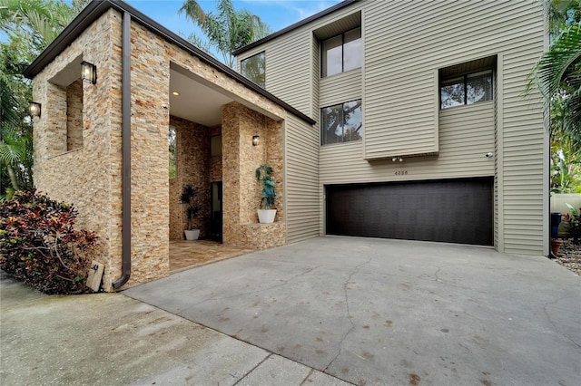 view of front of property with a garage, concrete driveway, and stone siding