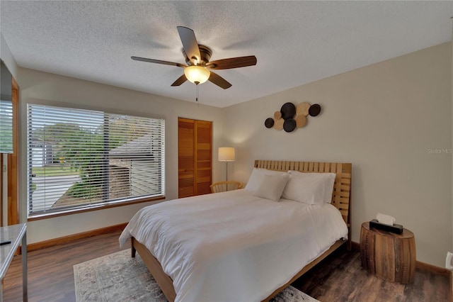 bedroom with a textured ceiling, wood finished floors, a ceiling fan, baseboards, and a closet