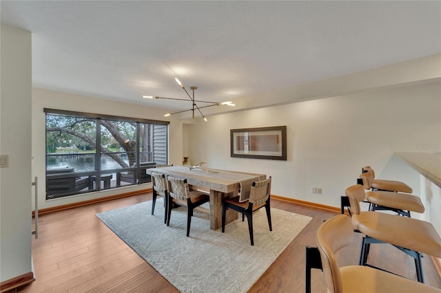 dining space featuring a notable chandelier, baseboards, and wood finished floors