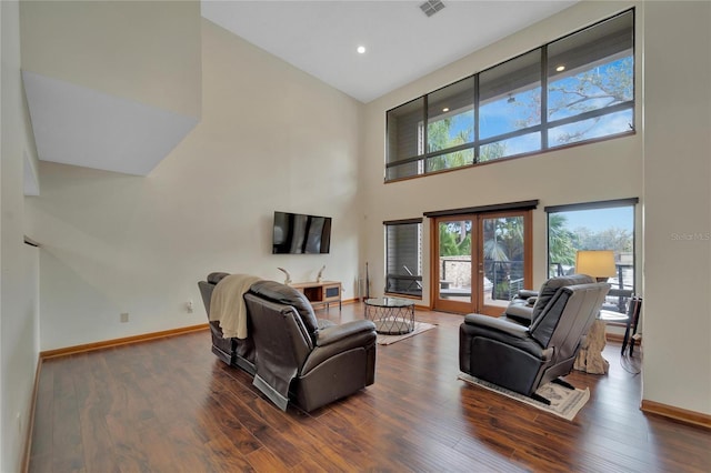 living area with high vaulted ceiling, baseboards, wood finished floors, and french doors