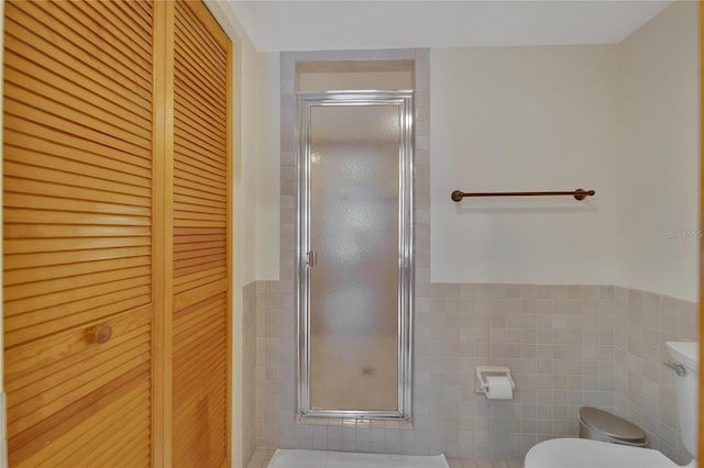 full bath featuring a stall shower, a closet, tile walls, and toilet