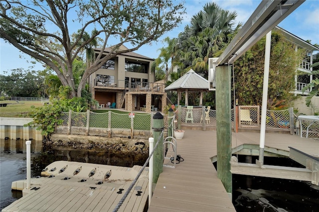 dock area featuring a water view, fence, and a gazebo