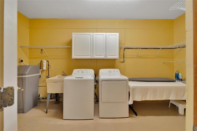 laundry room featuring a textured ceiling, washing machine and dryer, and cabinet space