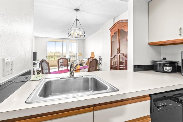 kitchen featuring black dishwasher, a notable chandelier, light countertops, hanging light fixtures, and a sink