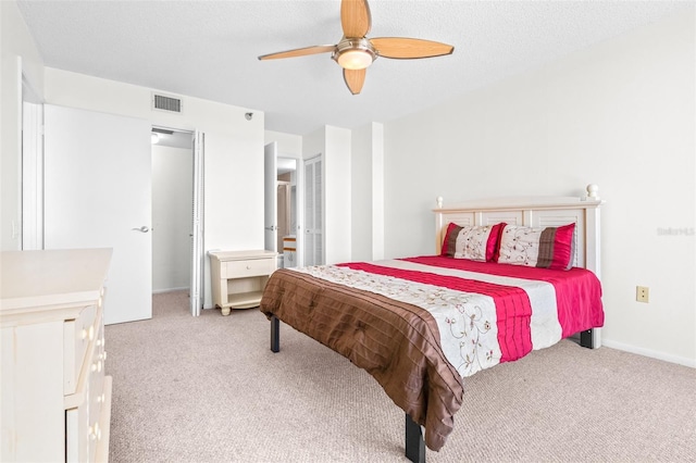 carpeted bedroom featuring baseboards, ceiling fan, visible vents, and a textured ceiling