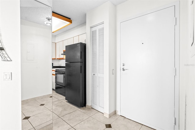 kitchen featuring black appliances, light tile patterned flooring, under cabinet range hood, and white cabinets