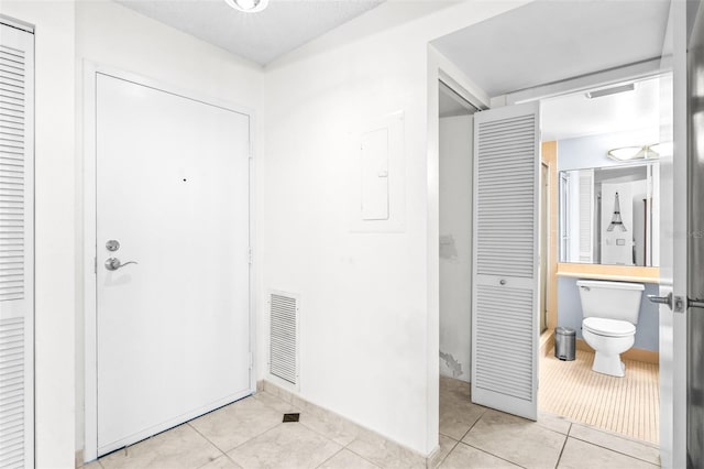 interior space featuring light tile patterned floors, electric panel, and visible vents