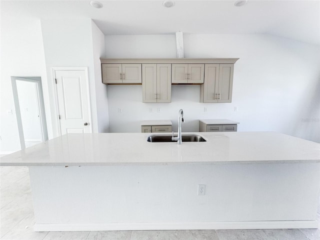 kitchen featuring an island with sink, vaulted ceiling, a sink, and gray cabinetry